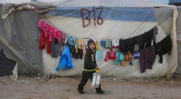 A young boy passes by a shelter on the way to collect water.