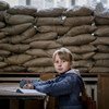 A child sits in a classroom in Ukraine with sandbags reinforcing the window to protect against shrapnel and bullets.