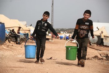 Two children collect drinking water in a camp for displaced people in Idlib, Syria.