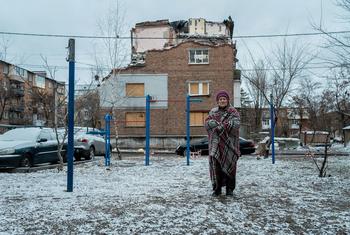 A woman stands outside her bomb-damaged home in Kharkiv, Ukraine.