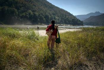 A young mother holds her one-year-old daughter as she flees to safety towards the border with Thailand during a one week journey by foot in January 2022, in eastern Myanmar.